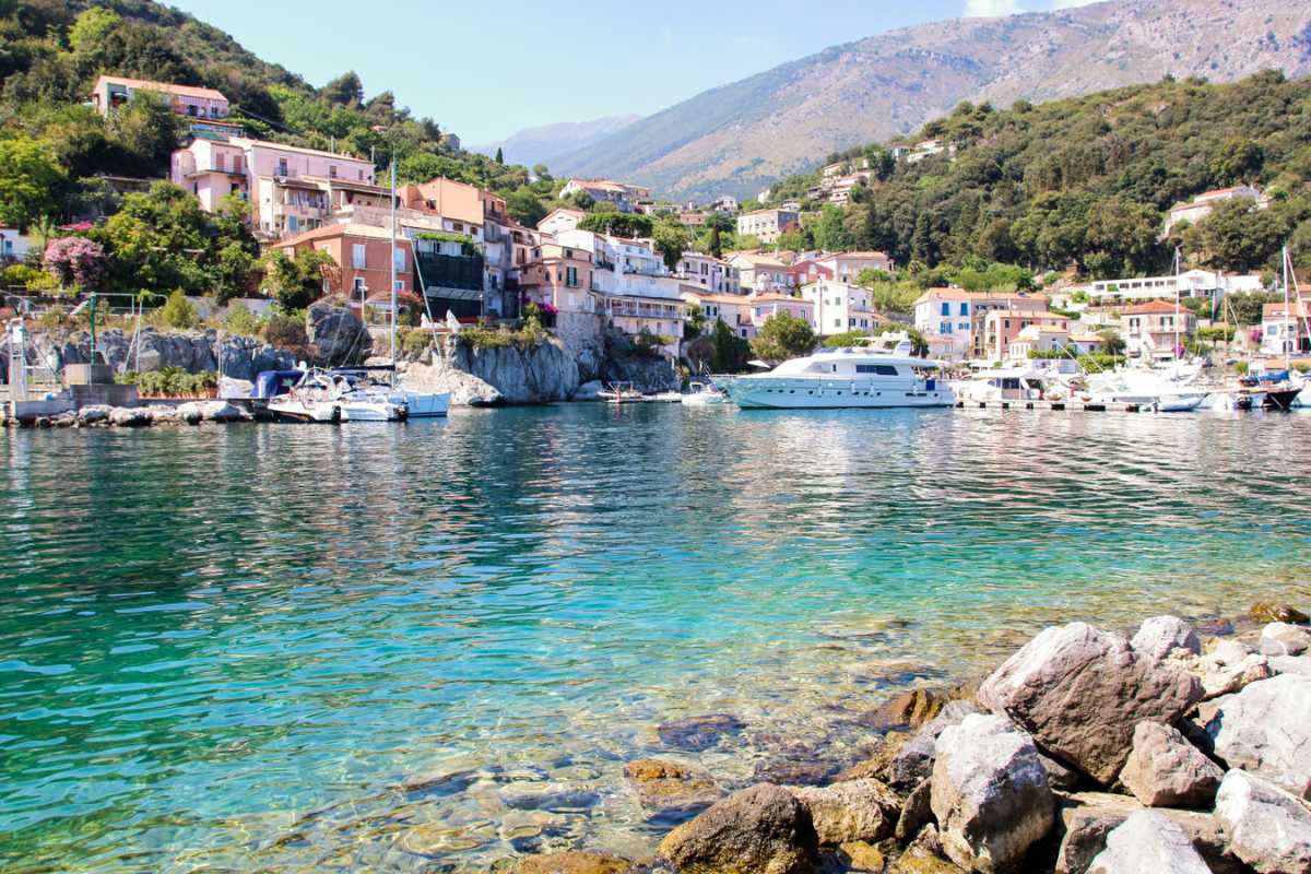 Scena serale durante la Sagra della Melanzana Ripiena: tavolate all’aperto, persone che degustano piatti tipici, luci calde, atmosfera conviviale, sullo sfondo scorcio del centro di Maratea